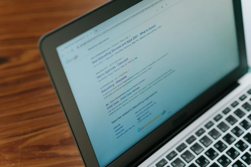A laptop on a wooden desk showing search engine results, demonstrating the importance of keywords and SEO in achieving a high Google ranking for my website.